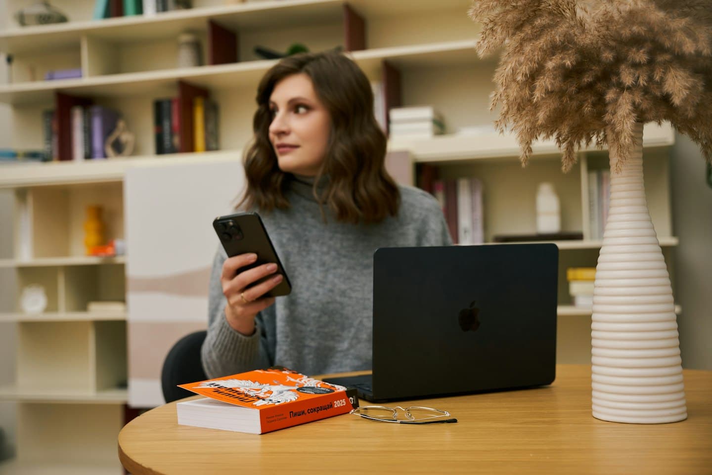 A saleswoman holding her phone in front of a laptop