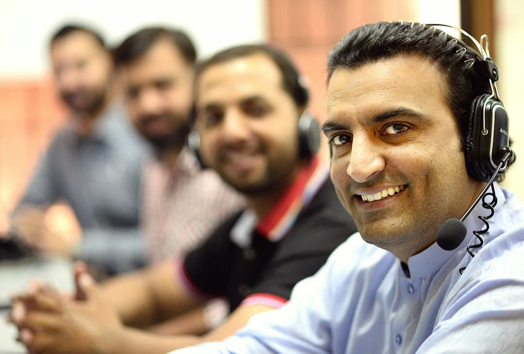A smiling support agent with a headset, the team behind him